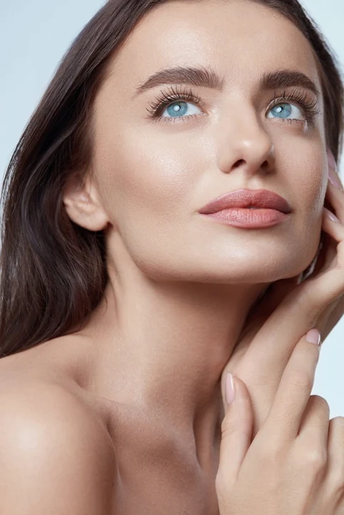 Beauty. Beautiful Woman Touching Face Close Up Portrait. Blue-Eyed Brunette Model With Perfect Skin And Natural Makeup Looking Away.